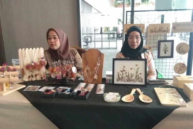 Sanih Supriatin (kanan) menunjukkan lukisan dan kalung bunga kering dari Buteka buatannya saat mengikuti gelar UMKM di sebuah hotel di Karawang, Jumat (30/12/202).