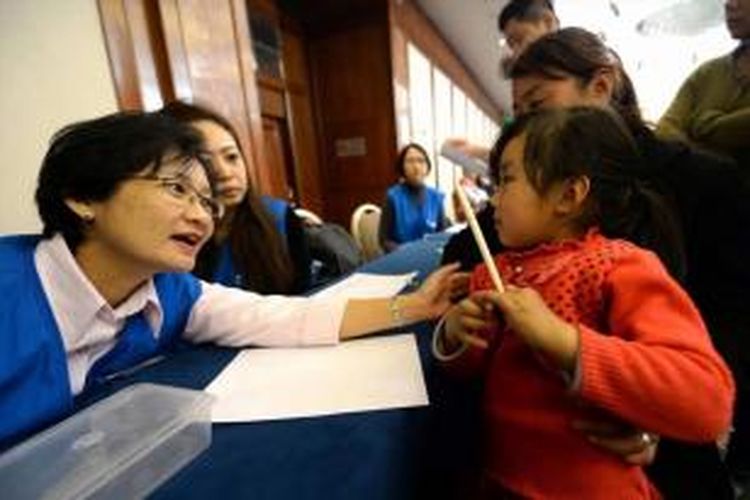 Petugas dari Malaysia Airlines menghibur seorang anak yang merupakan kerabat dari penumpang Malaysia Airlines yang hilang di Metro Park Lido Hotel di Beijing, China. Pemerintah Malaysia menyatakan pesawata tersebut jatuh di Samudra Hindia dan semua penumpang beserta awak tewas.