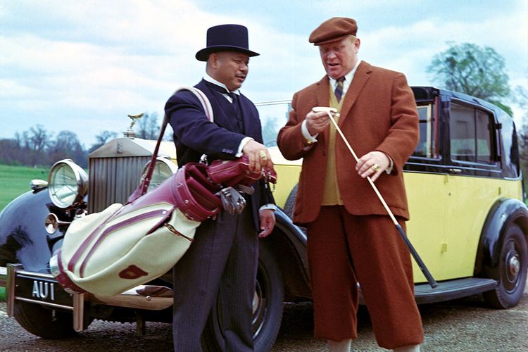 Sang tukang pukul Oddjob yang diperankan Harold Sakata (kiri) mengenakan senjata khasnya, sebuah topi bowler, dalam film James Bond, Goldfinger (1964). Topi itu dilelang dengan harga 30.000 poundsterling.