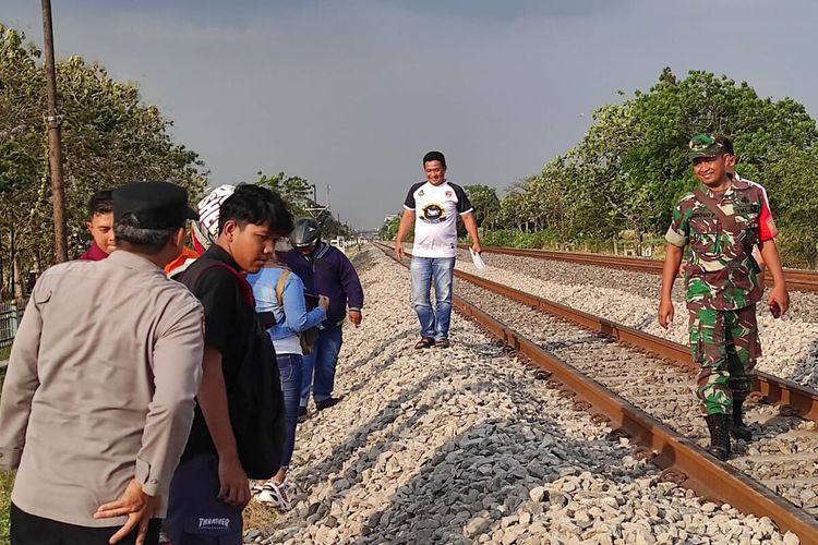 Petugas dan sejumlah warga mendatangi lokasi pengendara motor menghadang kereta api yang melintas di jalur kereta wilayah Desa Keplaksari, Kecamatan Peterongan, Kabupaten Jombang, Jawa Timur, Rabu (16/8/2023).