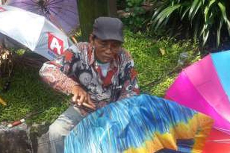 Sukrisno, kakek 68 tahun yang menjadi tukang payung saat memperbaiki payung di Jalan Gajah Mada, Kota Malang, Jawa Timur, Jumat (18/11/2016)