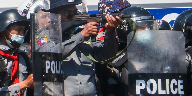 A police officer (C) aims a gun during clashes with protesters taking part in a demonstration against the military coup in Naypyidaw on February 9, 2021. (Photo by STR / AFP)