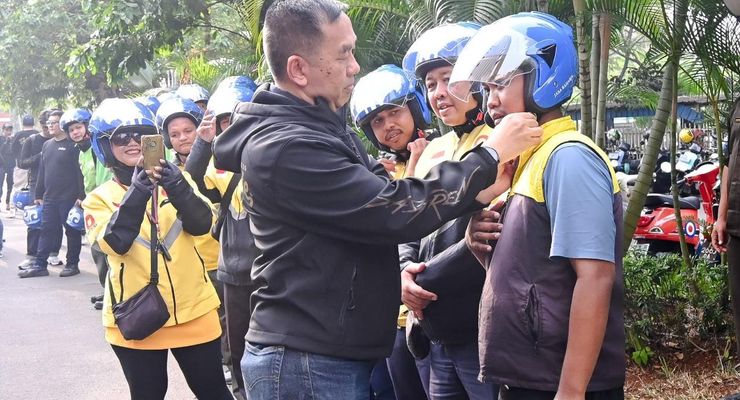 Direktur Utama Jasa Raharja Muhammad Awaluddin (jaket hitam) saat membagikan helm berstandar SNI kepada pengemudi ojek online sebagai bagian dari edukasi keselamatan berkendara pada kegiatan The Jasfren Ride yang berlangsung pada Minggu (13/9/2026).
