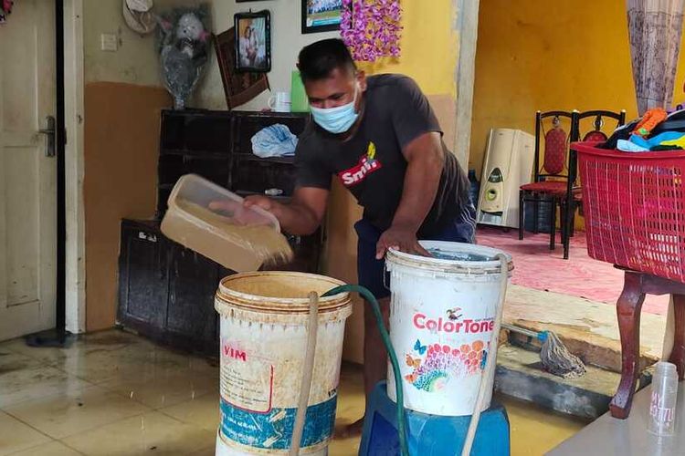 Rudi (33) menguras air di dalam rumahnya yang sudah dua hari dilanda banjir di Perumahan Pesona Harapan Indah, Kelurahan Tangkerang Labuai, Kecamatan Bukitraya, Kota Pekanbaru, Riau, Selasa (26/10/2021).