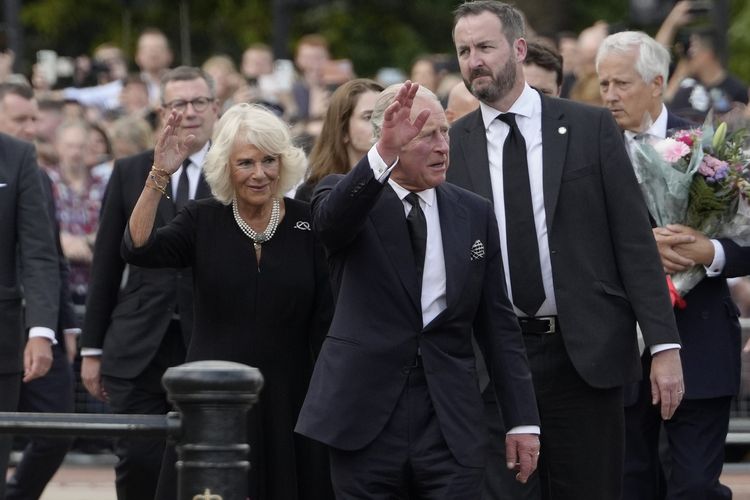 Raja Charles III dan Permaisuri Camilla melambaikan tangan saat tiba di Istana Buckingham, London, Jumat (9/9/2022). Charles naik takhta setelah Ratu Elizabeth II wafat pada Kamis (8/9/2022) dalam usia 96 tahun dan bertakhta selama 70 tahun.