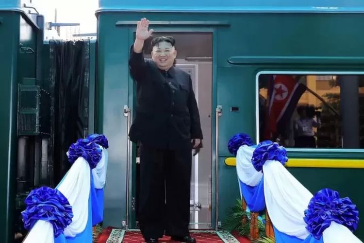 Kim Jong Un melambaikan tangan sebelum naik kereta untuk perjalanan.