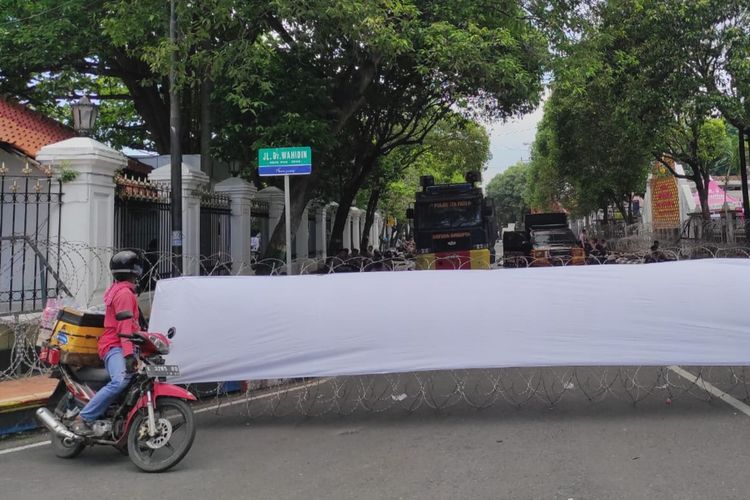 Salah seorang pedagang nampak kebingungan karena Jalan Dr Wahidin ditutup, jalan tersebut akses utama dan pemisah antara Gedung DPRD dan Pendopo Kabupaten Pati dipasang kawat berduri, Jumat (31/10/2025).