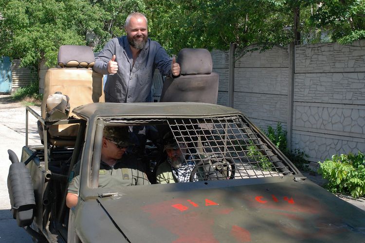 Volodymyr Tarkhov (belakang) berpose saat tentara Ukraina datang untuk memeriksa mobil tempur buatannya di bengkelnya di Zaporizhzhia, Ukraina, 15 Juni 2022 di tengah invasi Rusia. Di bengkel tersebut Tarkhov beserta teman-temannya mengubah mobil rally menjadi kendaraan tempur.