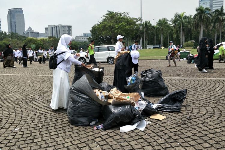Sejumlah peserta Reuni 212 berinisiatif mengumpulkan sampah di kawasan Monas, Jakarta Pusat, setelah acara tersebut berakhir, Minggu (2/12/2018) siang.