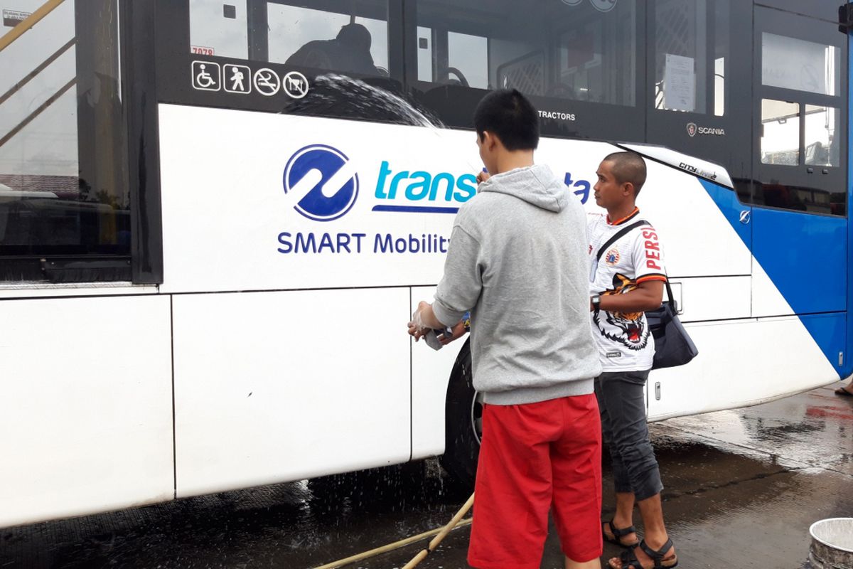 Jakmania membersihkan bus yang sempat dicoret usai laga Persiga vs Mitra Kukar pada Minggu (9/12/2018). Pembersihan dilakukan di kantor pusat PT Transjakarta, Jalan Mayjen Sutoyo, Cawang, Jakarta Timur, Kamis (13/12/2018)