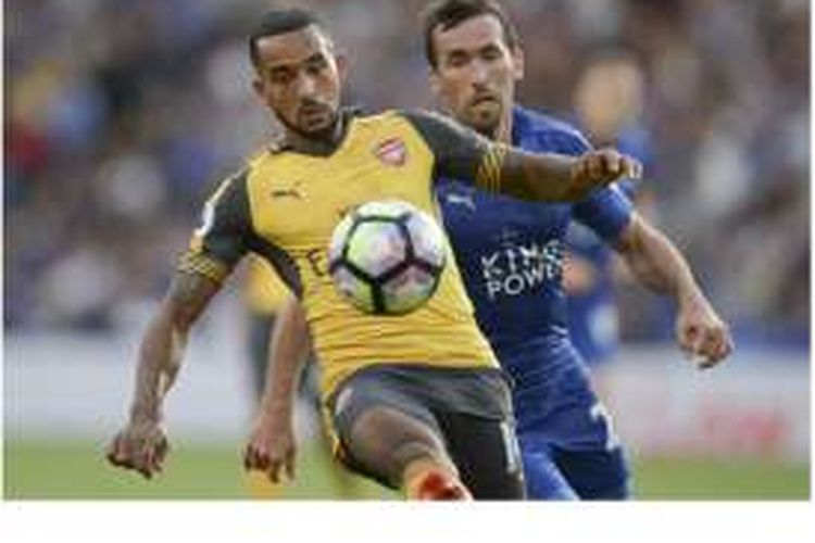 Gelandang Arsenal, Theo Walcott (kiri), berusaha melindungi bola dari rebutan bek Leicester City, Christian Fuchs, pada pertandingan Premier League di Stadion King Power, Leicester, Sabtu (20/8/2016).