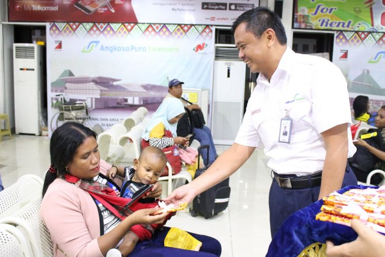 Petugas Bandara El Tari Kupang, sedang membagikan cokelat kepada para penumpang pesawat, Kamis (14/2/2019)