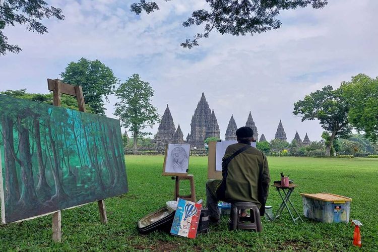 Seorang pelukis saat melukis di Taman area Candi Prambanan. Ada sembilan orang pelukis yang dihadirkan untuk mengabadikan Prambanan Dalam Sunyi dalam karya lukis, Senin (11/3/2024)