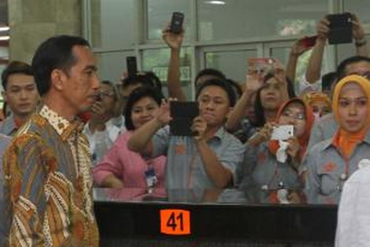 Petugas Kantor Pos berebut mengambil foto Presiden Joko Widodo saat peluncuran Keluarga Sejahtera dan Kartu Indonesia Sehat di Kantor Pos Indonesia, Jakarta Pusat, Senin (3/11/2014). Program Simpanan Keluarga Sejahtera tersebut akan dibagikan kepada kurang lebih 1 juta keluarga, sementara Kartu Indonesia Pintar akan dibagikan kepada 160.000 anak usia sekolah, dan untuk tahap pertama Kartu Indonesia Sehat diberikan kepada 4,5 juta individu di 19 kabupaten/kota di sembilan provinsi di Indonesia. TRIBUNNEWS/DANY PERMANA