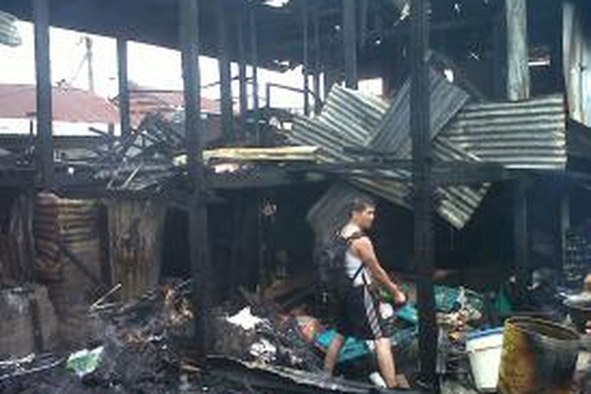 Salah seorang Warga memungut barang-barang berharganya yang tersisa dari puing-puing kebakaran di Jl Baji Gio, Makassar, Selasa (30/7/2013).