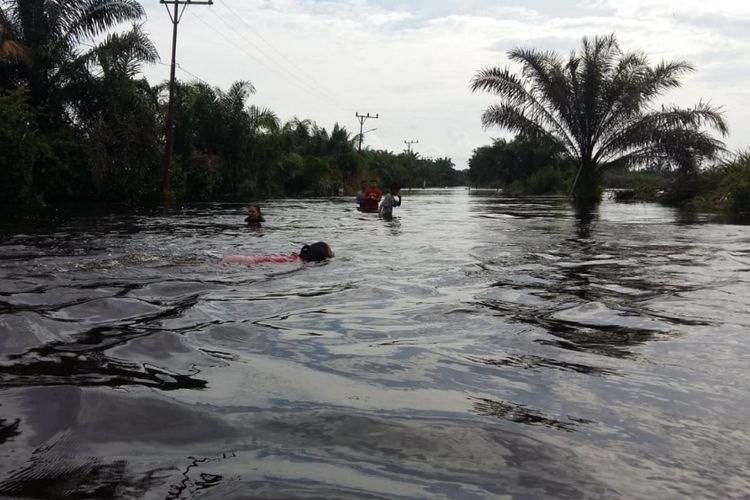 Anak-anak mandi di banjir yang melanda akses jalan menuju Desa Buluh Cina, Kecamatan Siak Hulu, Kabupaten Kampar, Riau, Selasa (18/12/2018)
