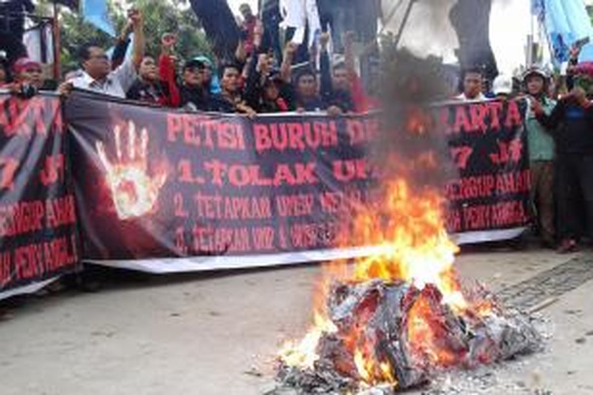 Kumpulan buruh berteriak di depan keranda mayat buatan dengan foto Gubernur DKI Jakarta Basuki Tjahaja Purnama atau Ahok yang telah terbakar di depan gedung Balaikota DKI Jakarta, Rabu (26/11/2014).
