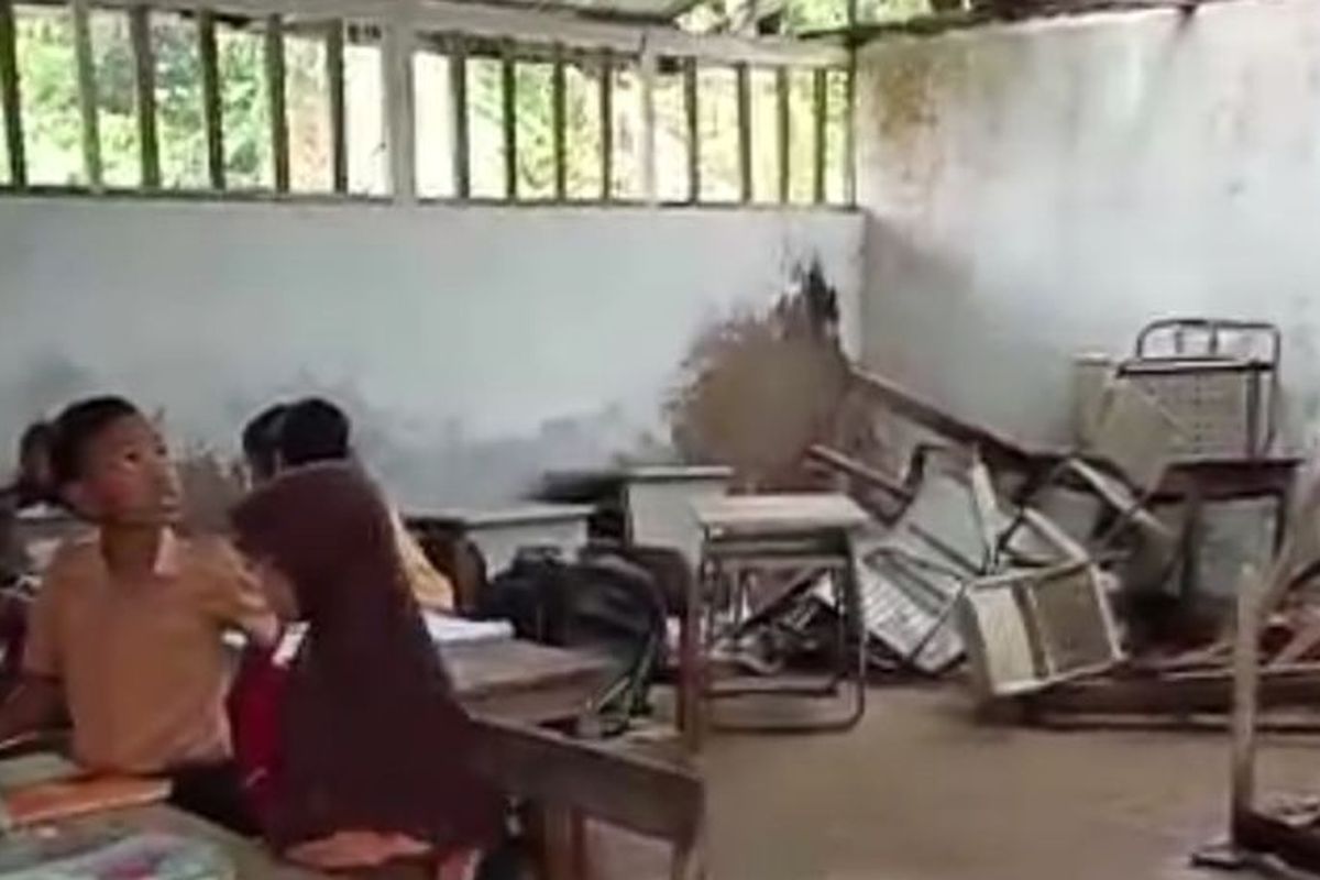Proses belajar siswa SDN Sabuntan III di dalam ruang kelas yang atapnya mengalami kebocoran. 