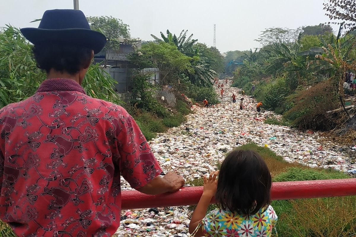 Warga menyaksikan operasi pengangkutan sampah di Kali Jambe, Kabupaten Bekasi, Jumat (6/9/2019).