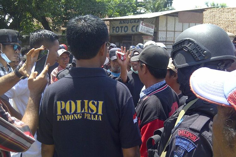 Puluhan warga saat berkerumunan dengan aparat di depan kantor Bupati Bima, Jumat (15/12/2017).