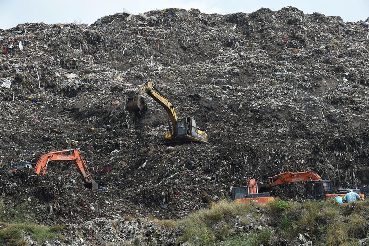 Operator excavator bersama dengan Layanan Kebakaran & Darurat Ahmedabad dan personel Polisi Gujarat melakukan pekerjaan pencarian setelah Neha Vasava yang berusia 12 tahun terkubur di bawah tumpukan sampah pada 26 September, ketika dia mengumpulkan bahan-bahan yang dapat didaur ulang, di tempat pembuangan sampah Pirana di pinggiran kota. di Ahmedabad pada 29 September 2020. Tim penyelamat dengan panik mengais-ngais pada 28 September untuk mencari seorang gadis 12 tahun yang diyakini terkubur selama dua hari di bawah tumpukan sampah besar yang runtuh saat dia sedang bekerja memulung. 