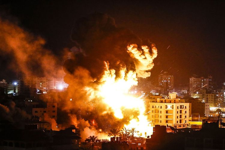 Asap disertai pijaran api membubung dari salah satu gedung di Gaza ketika jet tempur Israel menyerang sebagai bentuk balasan setelah roket menghantam Tel Aviv pada Senin (25/3/2019).