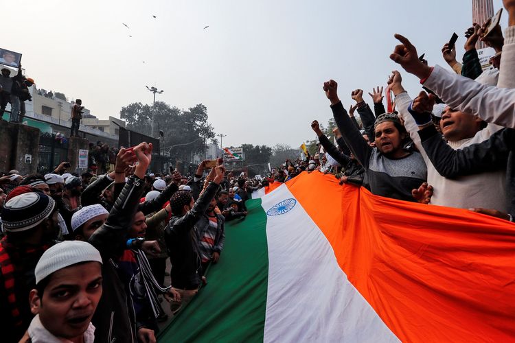 Demonstran membentangkan bendera India saat mereka melakukan aksi protes menentang UU Kewarganegaraan baru yang kontroversial, karena dianggap upaya memarjinalisasi Muslim di Masjid Jama New Delhi, Jumat (20/12/2019).
