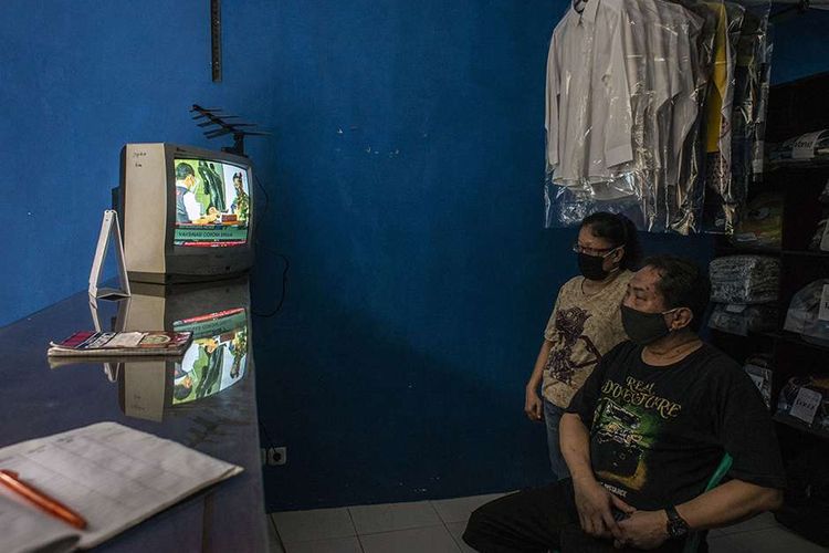 Warga menonton televisi yang menayangkan langsung penyuntikan vaksin Covid-19 perdana di Jakarta, Rabu (13/1/2021). Presiden Joko Widodo menjadi orang pertama di Indonesia yang disuntik vaksin Covid-19 buatan perusahaan farmasi Sinovac asal China itu usai BPOM mengeluarkan izin pengunaan darurat vaksin.
