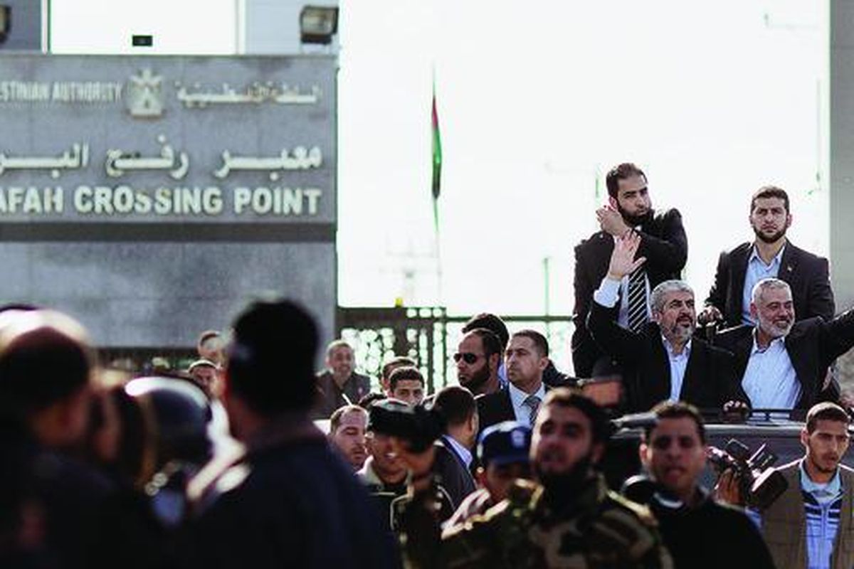 Pemimpin Hamas di pengasingan, Khaled Meshaal (kiri), dan pemimpin Hamas di Jalur Gaza, Ismail Haniya (kanan), melambaikan tangan dari mobil terbuka dalam parade menyambut kedatangan Meshaal di Rafah, Jumat (7/11). Ini adalah kedatangan pertama Meshaal ke Jalur Gaza. 