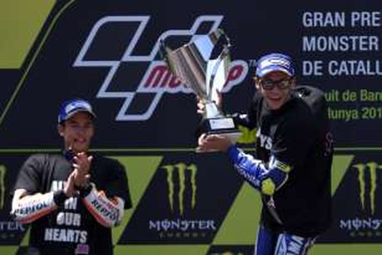 Pebalap Movistar Yamaha asal Italia, Valentino Rossi (kanan), mengangkat trofi juara setelah finis pertama pada GP Catalunya di Sirkuit de Barcelona-Catalunya, Minggu (5/6/2016). Pebalap Repsol Honda, Marc Marquez, finis di ruutan kedua.