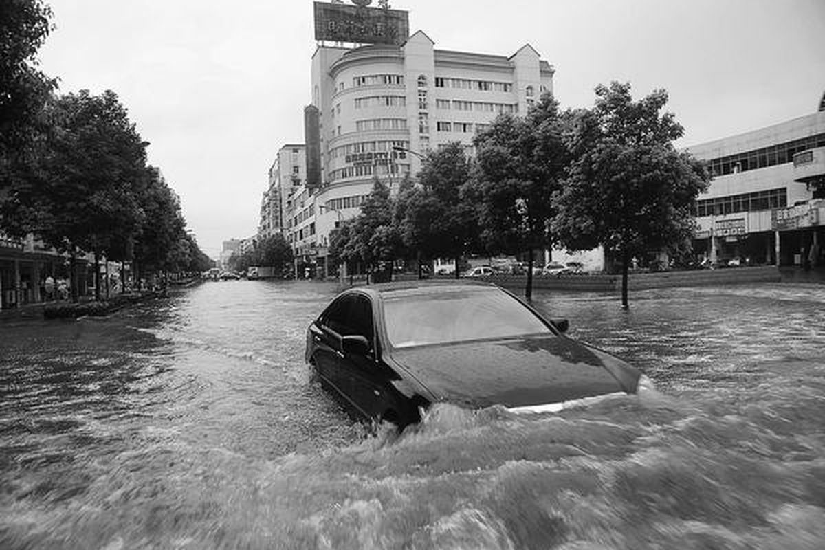 Sebuah mobil terpaksa harus menerjang air bah yang melanda sebuah jalan di Yingtan, Provinsi Jiangxi, Sabtu (19/6). Banjir dan tanah longsor melanda sebagian wilayah China selatan; menyebabkan setidaknya 90 orang tewas dan 50 dinyatakan hilang, sampai hari Sabtu