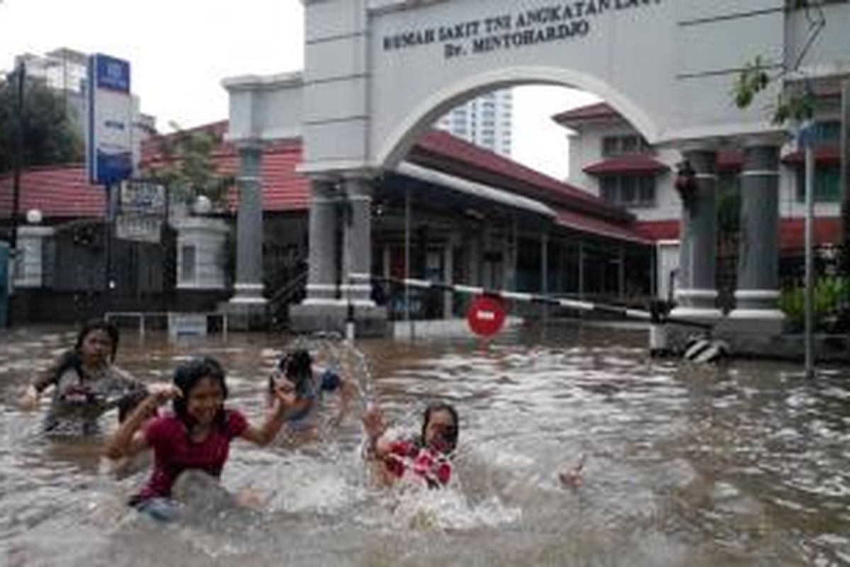 Anak-anak bermain di tengah banjir yang merendam kawasan Bendungan Hilir, Jakarta Pusat, Senin (13/1/2014).