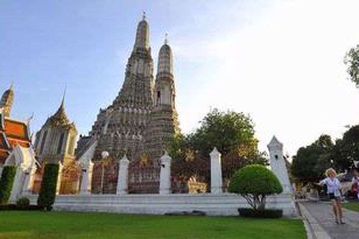 Pengunjung berjalan di depan Candi Wat Arun di Bangkok, Thailand, Rabu (27/4/2011). Wat Arun yang dibangun sekitar abad 18 ini terletak di sebelah barat sungai Chao Praya dan merupakan salah candi Budha yang menjadi ikon wisata Thailand.