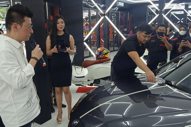 CEO Topcoat Lampung Revo Avi Salendra menuangkan cairan di bodi mobil yang sudah dilapisi paint protection dalam peragaan grand launching, Minggu (19/6/2022).