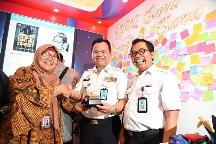 Kasubag Penerangan Humas DPR RI, Erna Agustina saat memberikan cinderamata pada pengunjung booth Humas Biro Pemberitaan Parlemen.