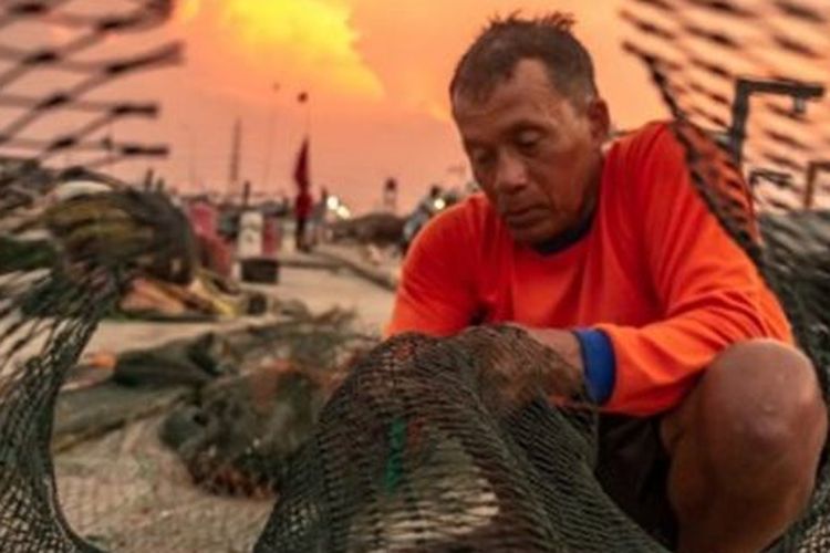 Seorang nelayan memperbaiki jaring di kawasan dermaga Kampung Bahari Tambaklorok, Semarang, Jawa Tengah, Senin (18/11/2019). 