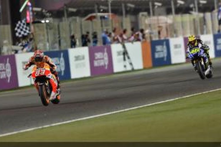 Pebalap Repsol Honda asal Spanyol, Marc Marquez, menyentuh garis finis di depan pebalap Movistar Yamaha, Valentino Rossi, pada GP Qatar di Sirkuit Losail, Minggu (23/3/2014).