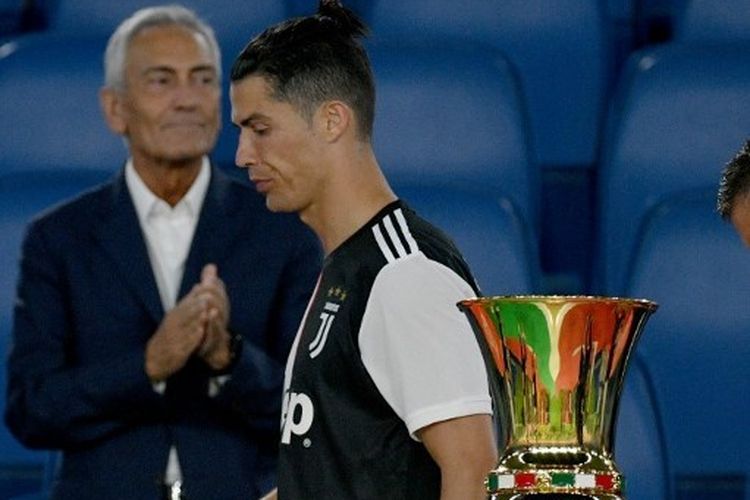 Cristiano Ronaldo berjalan melewati trofi Coppa Italia. 