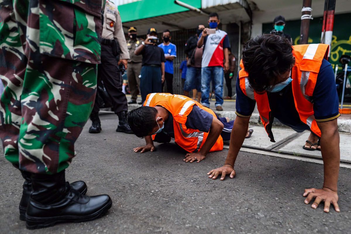 Petugas gabungan menghukum warga yang tidak menggunakan masker dengan melakukan push up saat patroli penegakan aturan pembatasan sosial berskala besar (PSBB) di Jl. Matraman Raya, Kecamatan Jatinegara, Jakarta Timur, Selasa (19/5/2020). Dalam kegiatan patroli PSBB tersebut, target penegakan untuk masyarakat yang tidak mengunakan masker dijalanan.