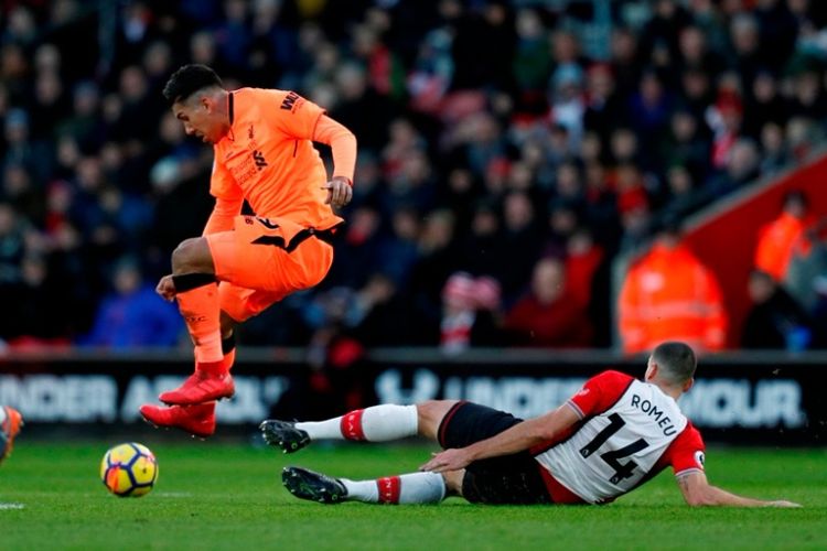 Penyerang Liverpool FC, Roberto Firmino (tengah), melompat dari hadangan gelandang Southampton, Oriol Romeu, dalam laga Premier League di Stadion St. Marys, Southampton, pada 11 Februari 2018. 