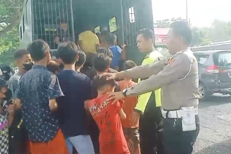 Anggota Satlantas Polres Bangkalan, Jawa Timur, menaikkan anak-anak asal asal Surabaya ke dalam truk yang nyebrang Jembatan Suramadu, Sabtu (16/12/2023) untuk berenang di sungai Desa Tunjung, Kecamatan Burneh, Kabupaten Bangkalan.