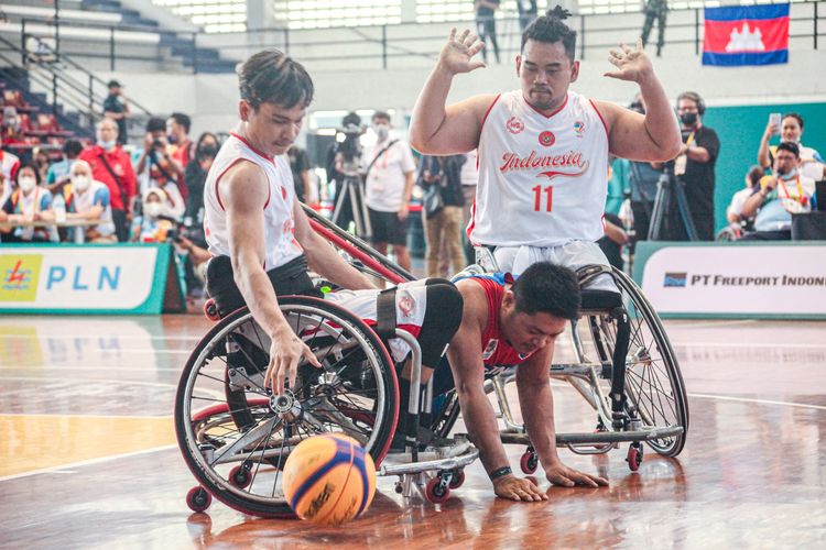 Pemain Filipina terjatuh setelah diapit oleh pemain timnas wheelchair basket Indonesia, Kasep Ayatulloh (kanan) dan Ivo Shadah (kiri) pada laga pernada ASEAN Para Games 2022 cabor basket 3x3, Sabtu (30/7/2022) siang WIB.