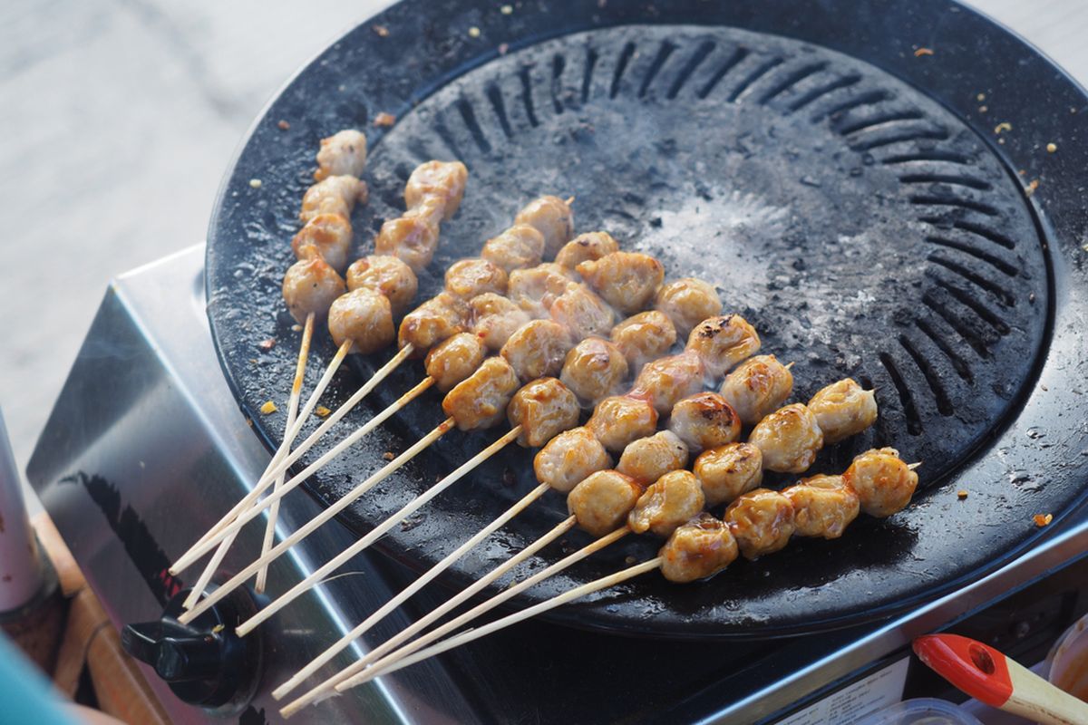 Ilustrasi sate bakso bakar di atas grill pan. 