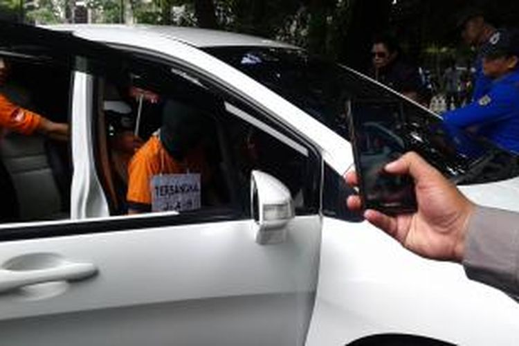 Tersangka pembunuh Sri Wahyuni (42), Jean Alter Huliselan (31) atau JAH, masuk ke dalam mobil, mengulangi adegan pembunuhan yang dilakukan di Jalan Prapanca Raya, Jakarta Selatan, Rabu (10/12/2014).
