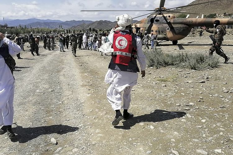 Upaya penyelamatan korban gempa Afghanistan 2022 oleh tentara dan petugas Bulan Sabit Merah Afghanistan. Tim penyelamat berjalan di dekat helikopter di daerah yang dilanda gempa di distrik Gayan, provinsi Paktika, Afghanistan.