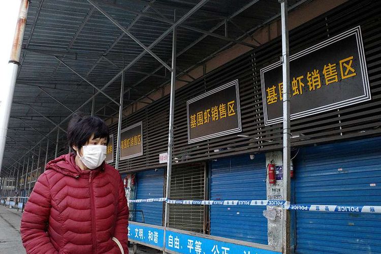 Seorang perempuan melintas di depan pasar ikan di Kota Wuhan, China, yang ditutup terkait dugaan sebagai lokasi awal merebaknya virus misterius di negara itu, Minggu (12/1/2020). Virus misterius mirip pneumonia telah menjangkiti puluhan orang dan menelan korban jiwa kedua di China, menurut pemerintah setempat.