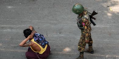 Seorang tentara berdiri di belakang seorang pria yang ditahan, dalam demonstrasi menentang kudeta di Mandalay, Myanmar, pada 3 Maret 2021.