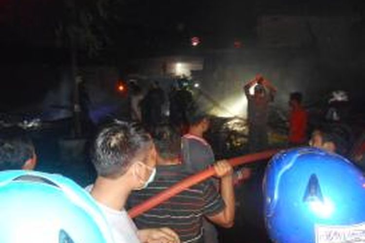 Petugas dibantu warga berusaha memadamkan api yang membakar lima kios di jalan Sampangan Demak, Jumat (14/8/2015) malam.