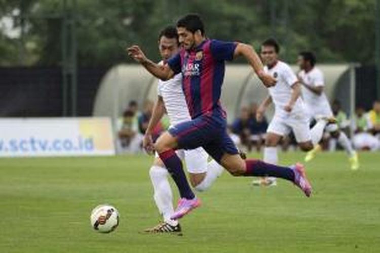 Pemain Barcelona Luis Suarez (depan) berebut bola dengan pemain Timnas Indonesia U-19 Sahrul Kurniawan dalam pertandingan persahabatan antara FC Barcelona B vs Timnas Indonesia U-19 di Pusat Olahraga FC Barcelona Joan Gamper, Sant Joan Despi, Spanyol, 24 September 2014.