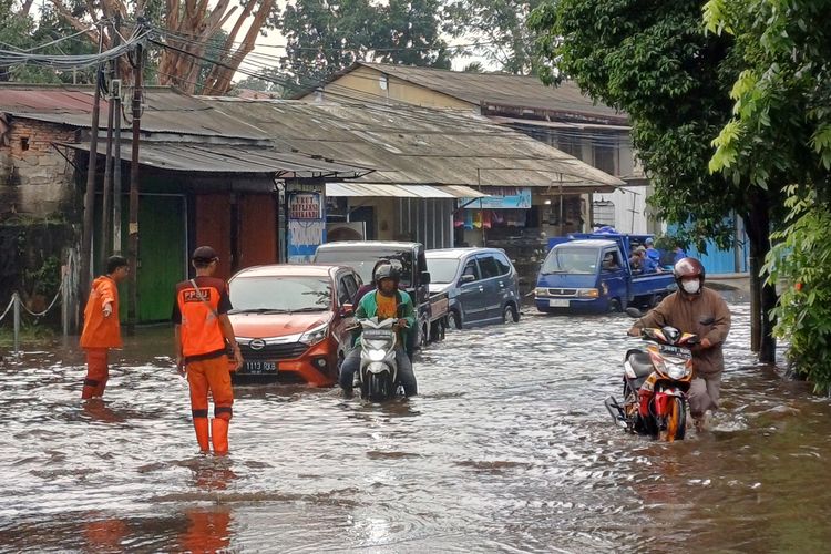 Salah satu pengendara motor saat menuntun motornya yang mogok karena menerobos banjir di Jalan Jambore, Cibubur, Jakarta Timur,  Minggu (21/4/2024).